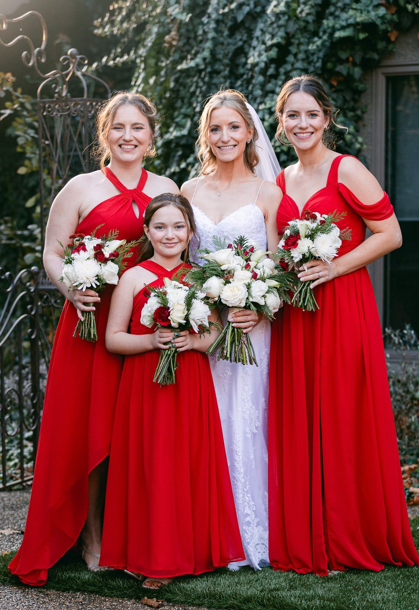 A bride and her bridesmaids are posing for a picture in red dresses.