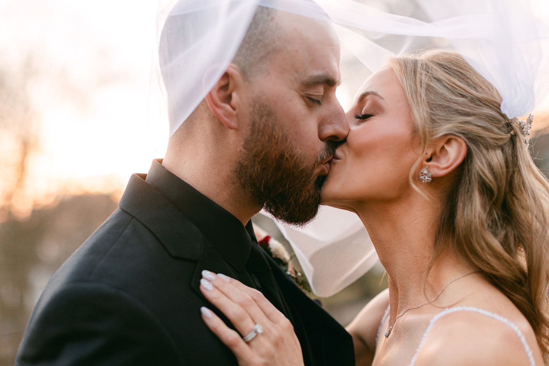 A bride and groom are kissing under a veil.