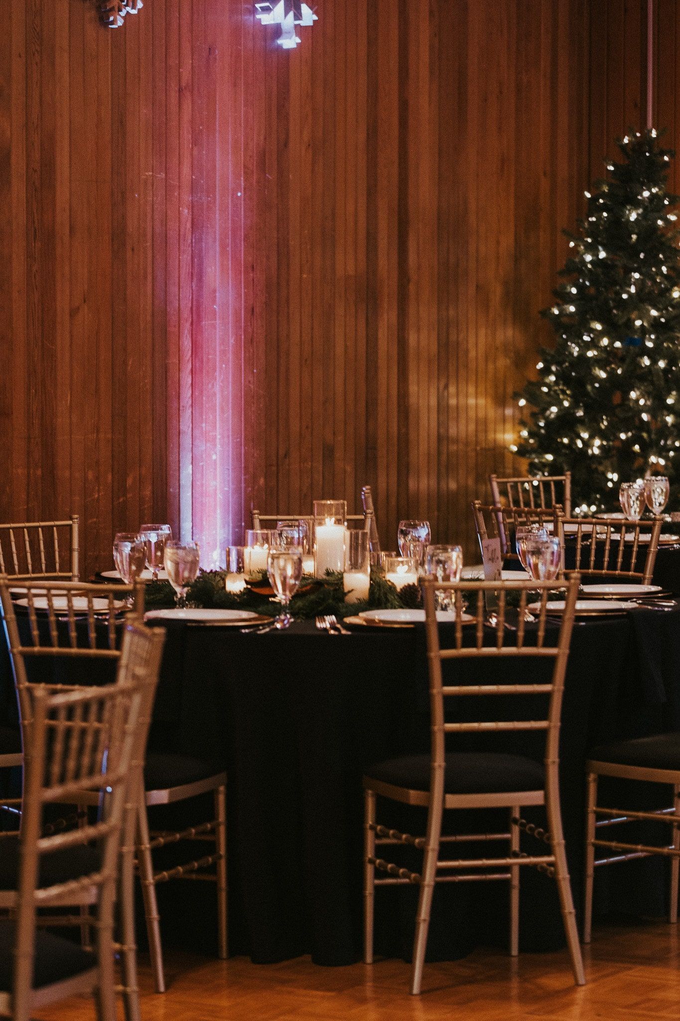 A room with tables and chairs and a christmas tree in the background