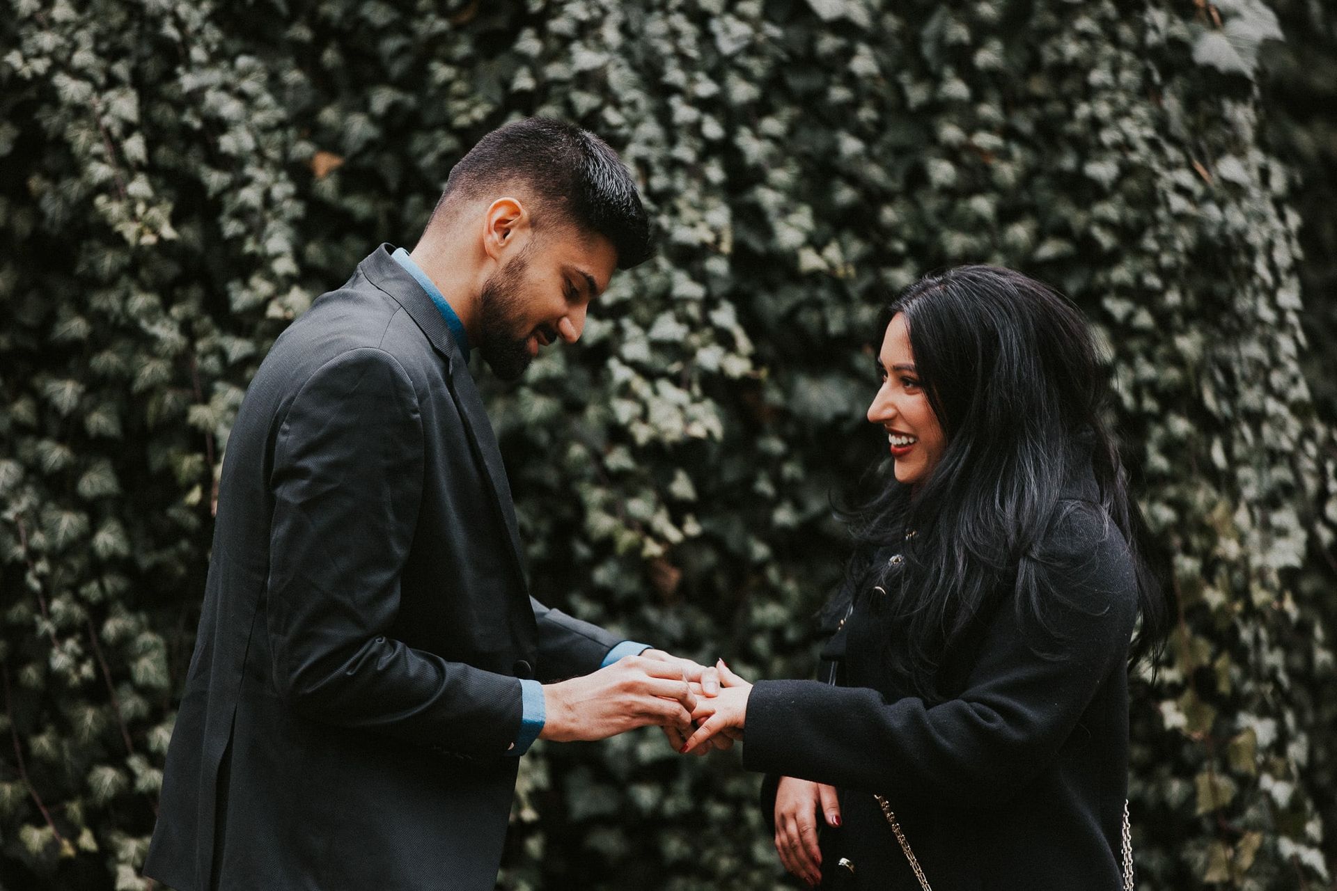 A man is putting a ring on a woman 's finger.