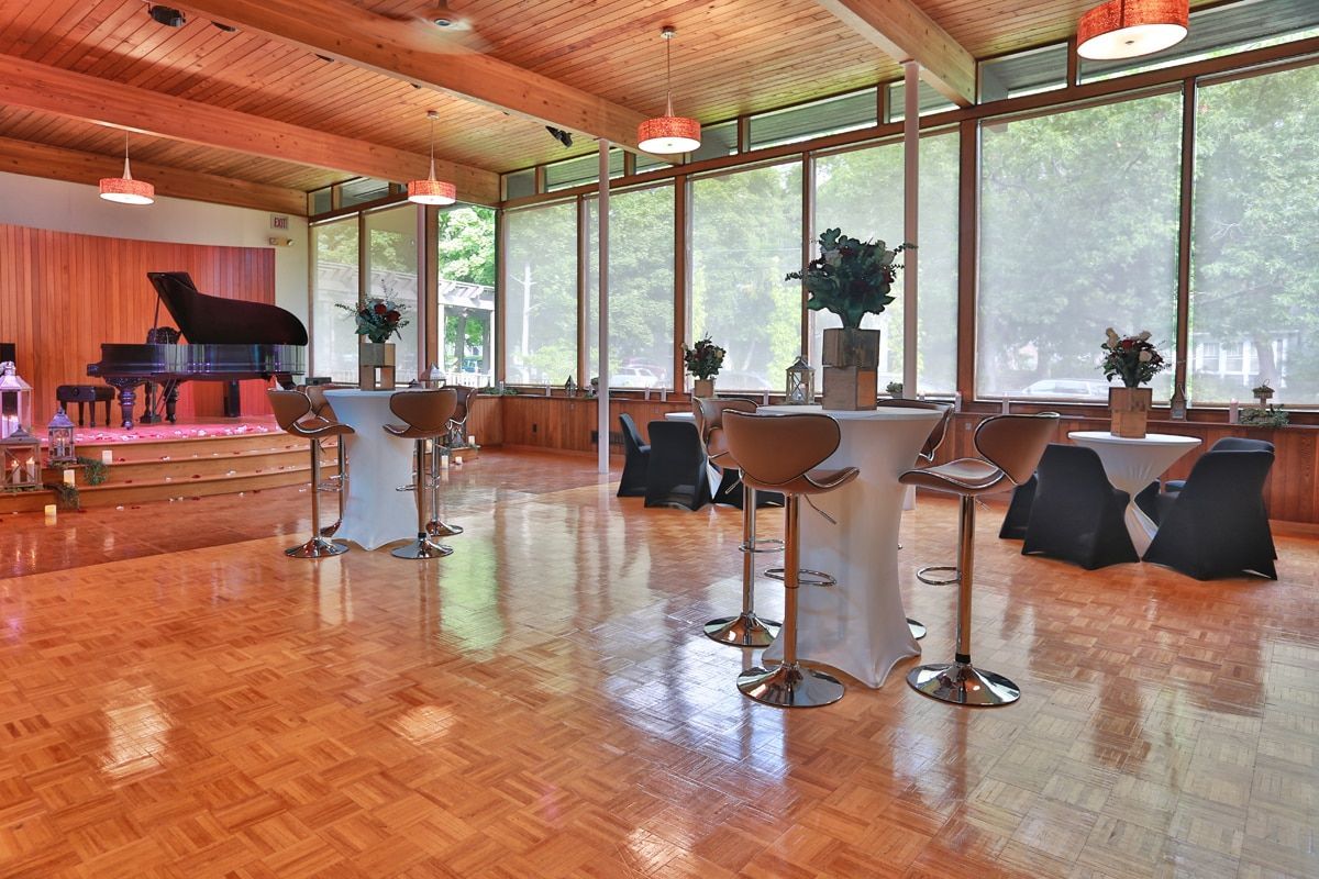 A large room with tables and chairs and a piano.