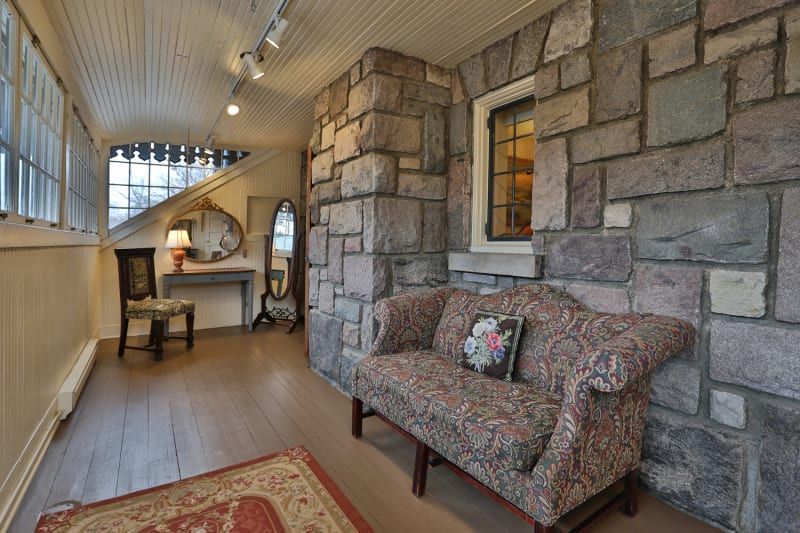 A couch is sitting in a hallway next to a stone wall.