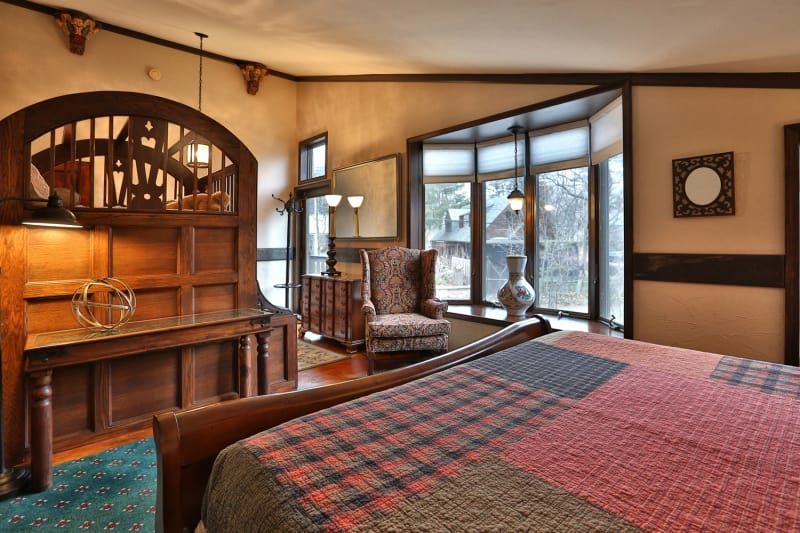 A bedroom with a large bed , chair , table and window.