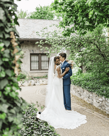 A bride and groom are standing next to each other in front of a building.