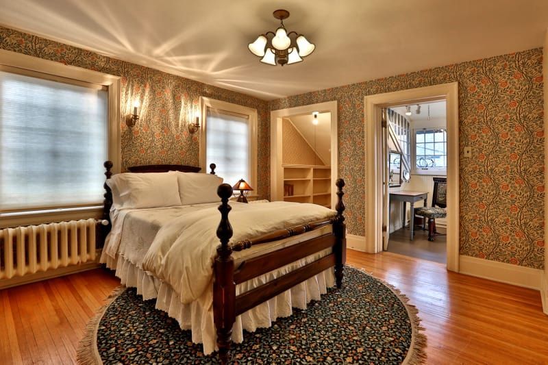 A bedroom with a bed and a rug on the floor