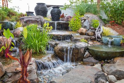 A waterfall is surrounded by rocks and plants in a garden.