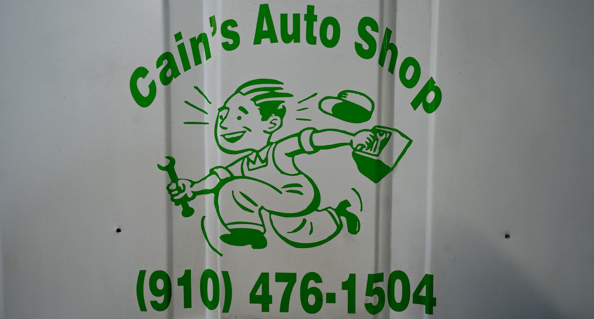 Cain's Auto Shop logo: cartoon man running with wrench, hat, and paperwork, with business name and phone number (910) 476-1504. | Cain's Auto Shop