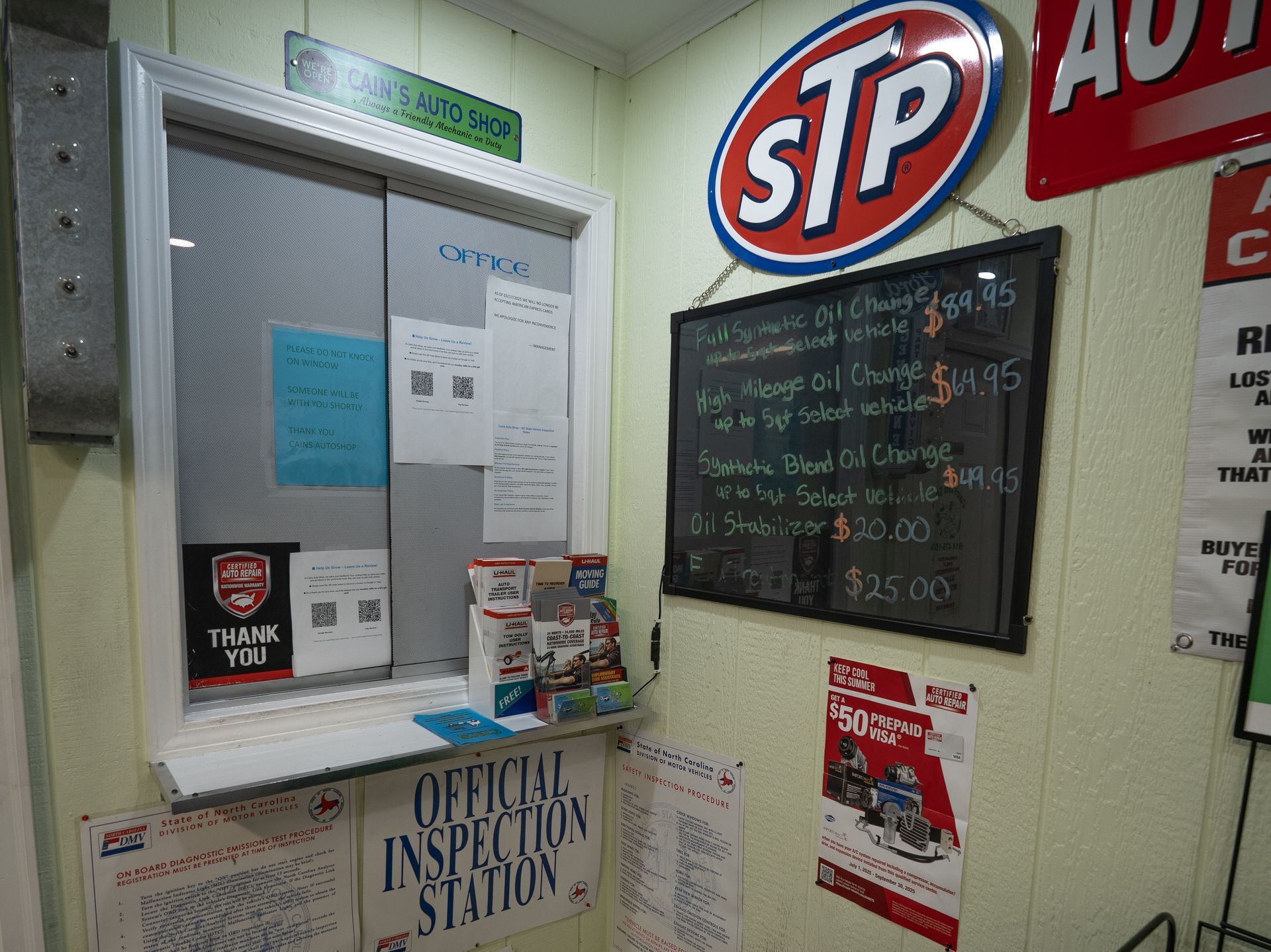 Service station office with a window, STP sign, and oil change prices on a chalkboard. | Cain's Auto Shop