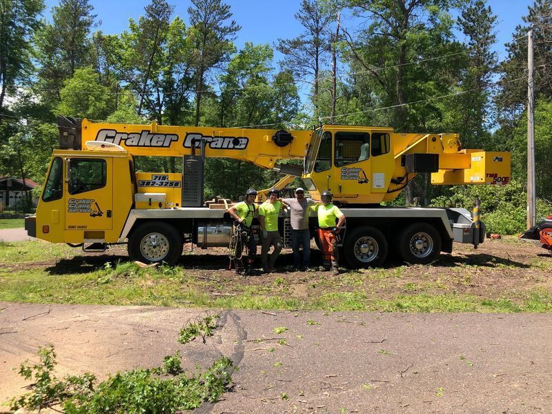 A group of men are standing in front of a yellow crane.