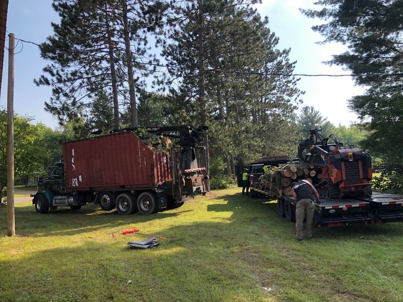 A truck with a red container on the back is parked in a grassy field.