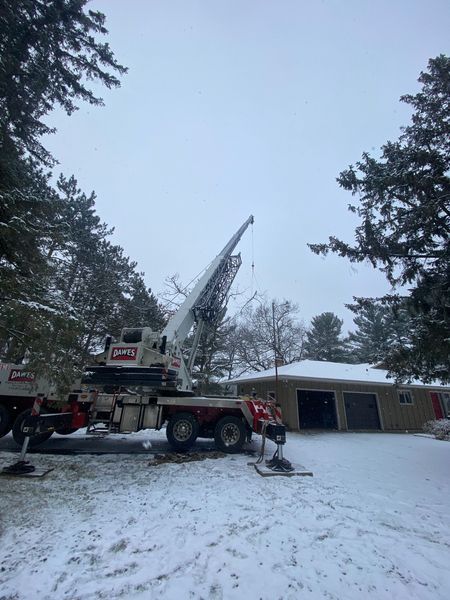 A crane is sitting in the snow in front of a house.