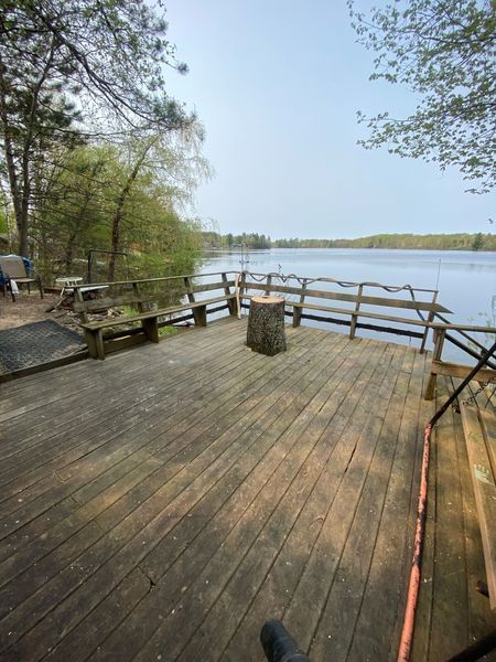 A wooden deck overlooking a lake with trees in the background