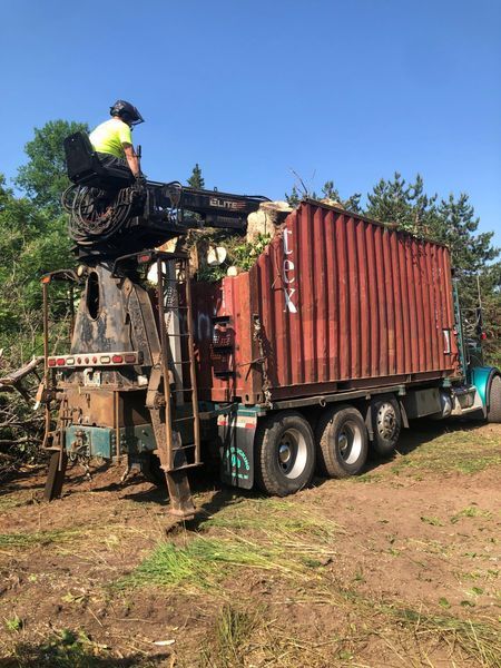 A man is sitting on top of a truck with a crane attached to it.