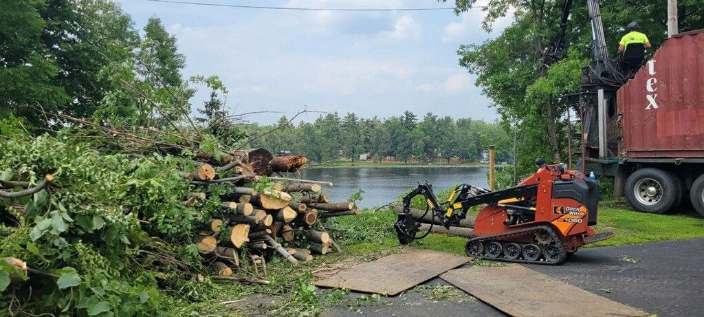 A truck is driving down a road next to a pile of logs.