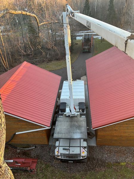A white truck with a crane attached to it is parked in front of two houses with red roofs.