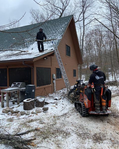 Two men are working on the roof of a house in the snow.