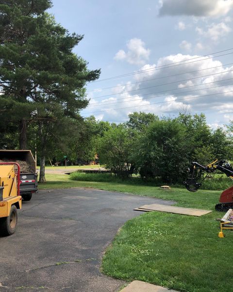 A yellow truck is parked in a driveway next to a red truck.