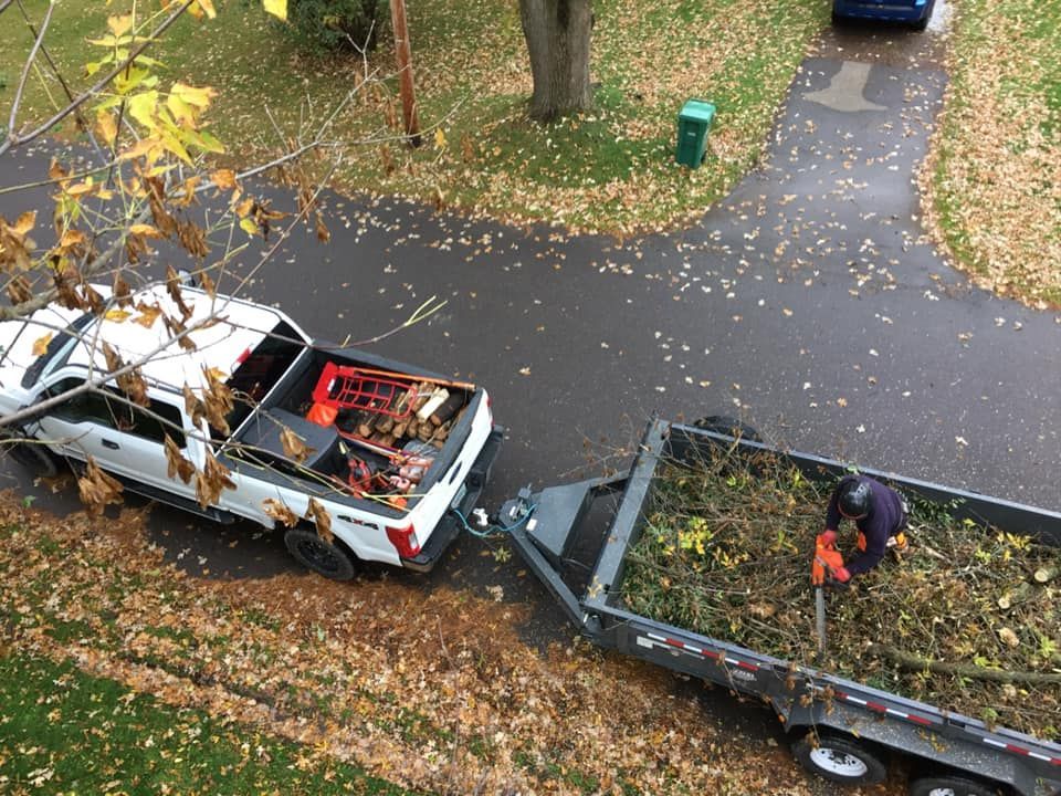 A white truck is pulling a trailer full of leaves.