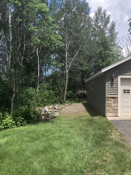 A house with a garage and a driveway surrounded by trees.