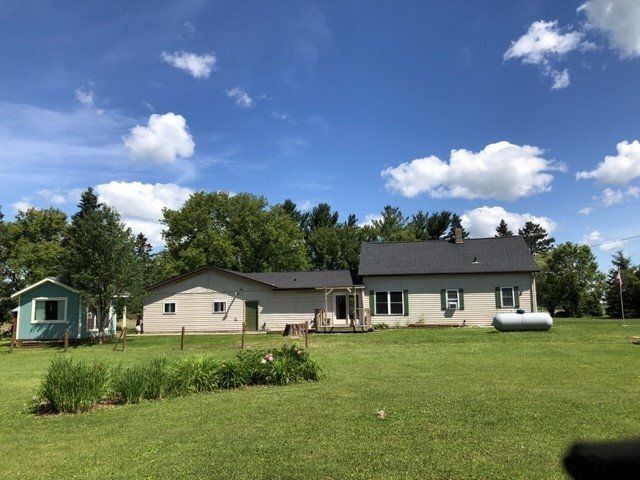 A house is sitting in the middle of a lush green field.