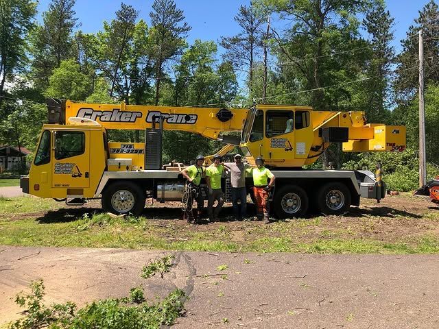 A group of men are standing in front of a yellow crane truck.