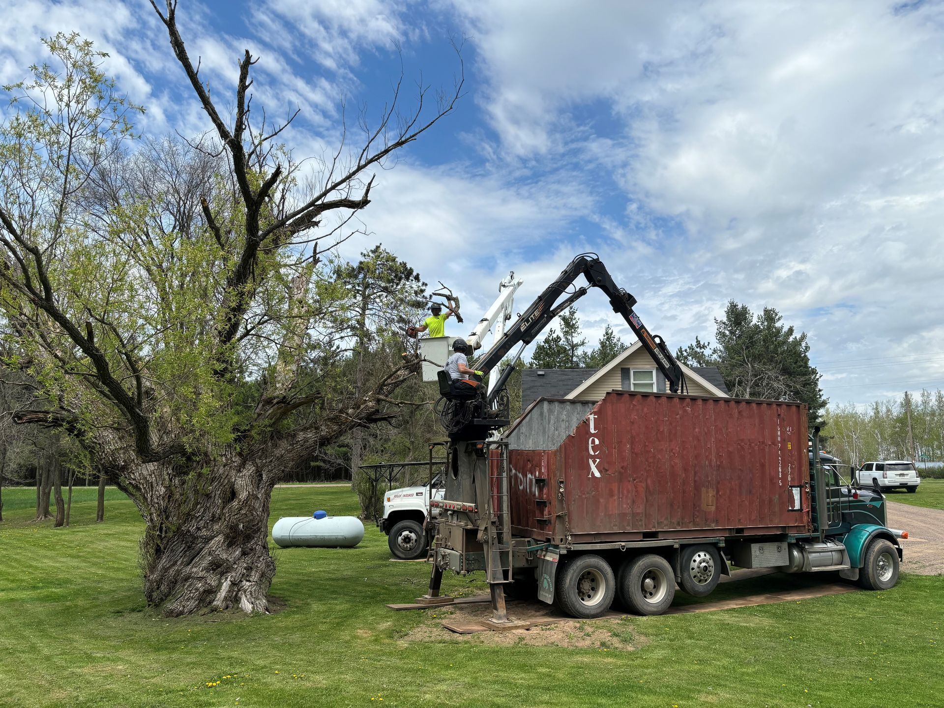 A truck is carrying a red shipping container in a field.