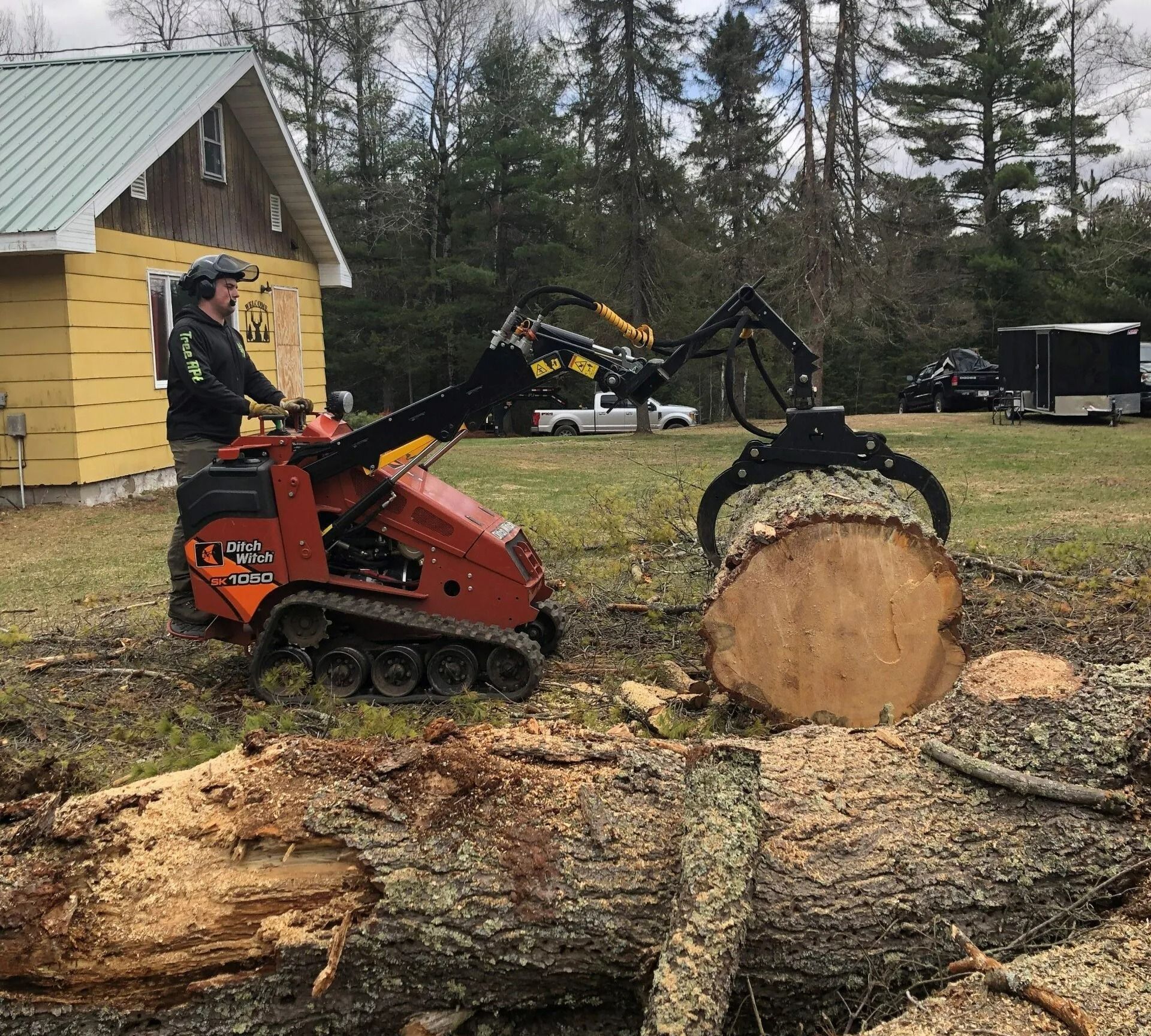 A man is riding a tractor next to a large log
