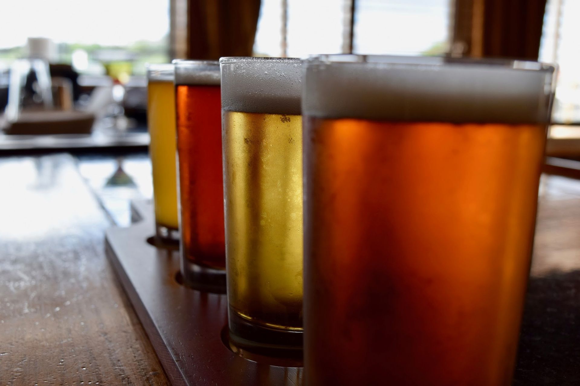 A tray of beer glasses sitting on top of a wooden table.