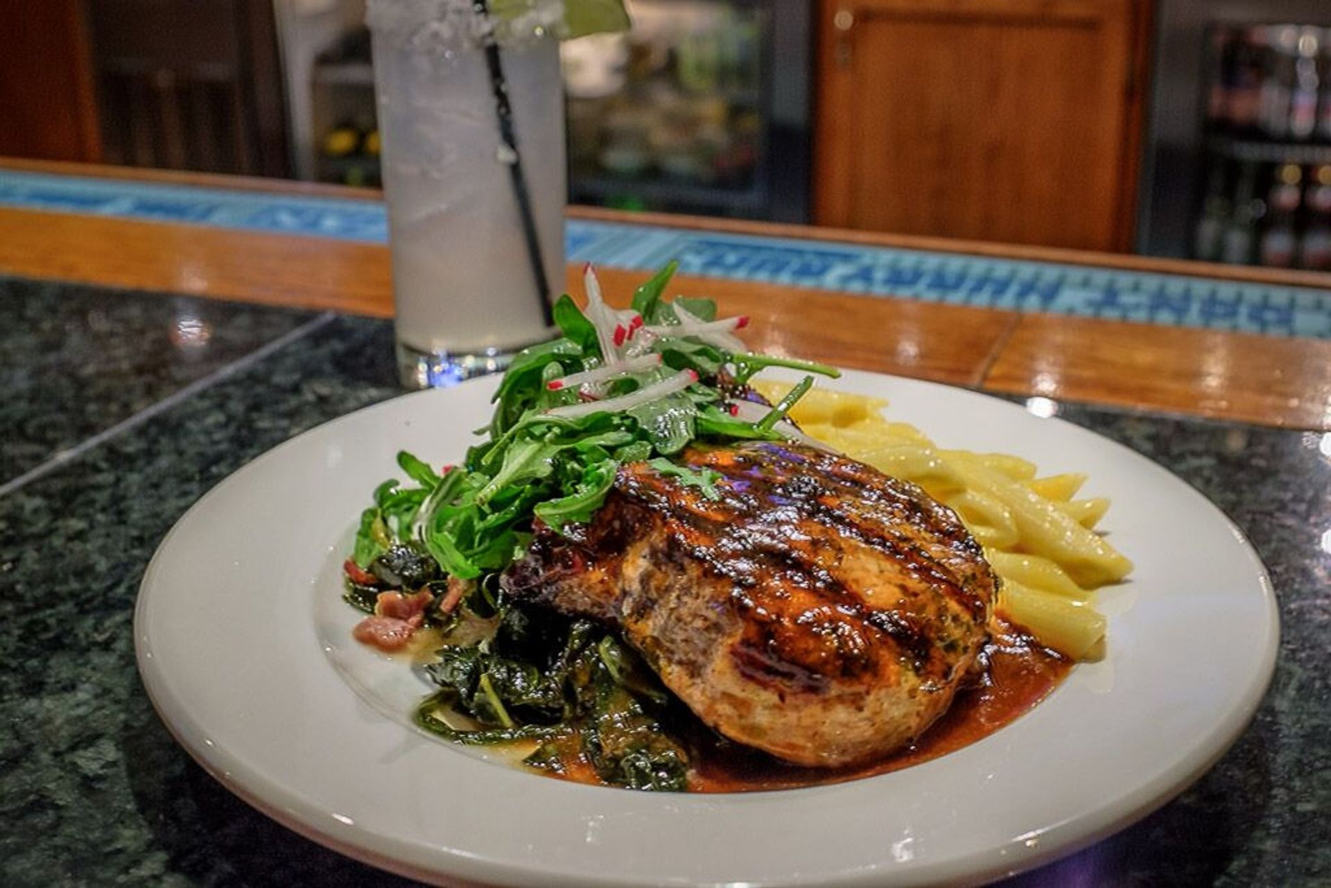 A white plate topped with a chicken breast and french fries on a table.