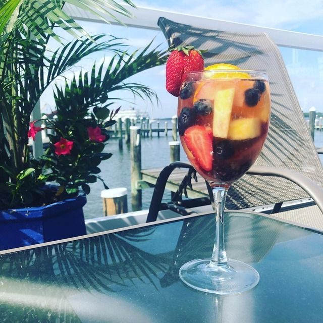 A wine glass filled with fruit sits on a glass table