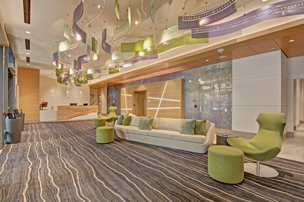 A lobby with a couch, chairs, and ottomans at Tower12 Apartments.