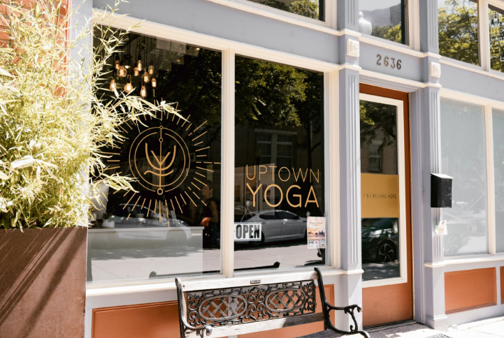 Exterior storefront of Uptown Yoga in Dallas TX located at 2636 Thomas Ave showing the gold logo on the window.