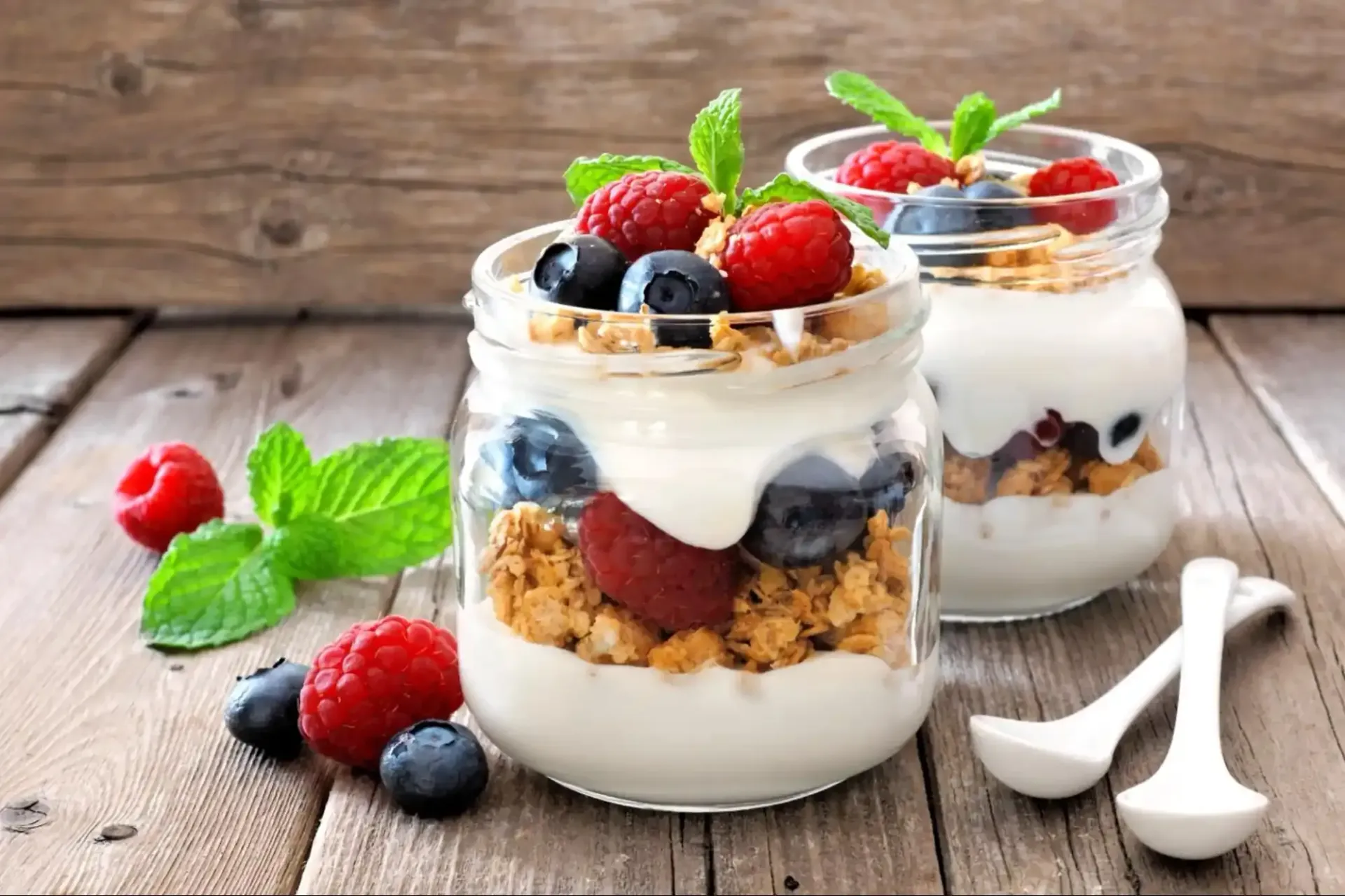 Two glass jars of yogurt, granola, and fresh berries prepared as a healthy pre-yoga snack at Uptown