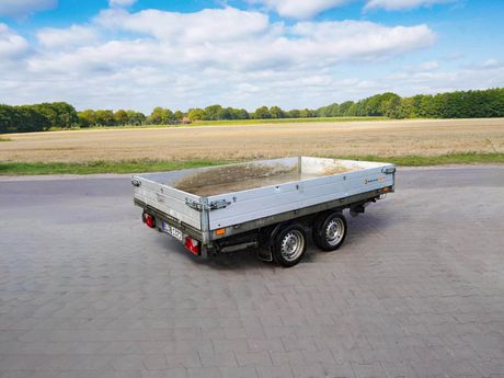 Grauer Anhänger von SARIS steht auf einer gepflasterten Fläche.
