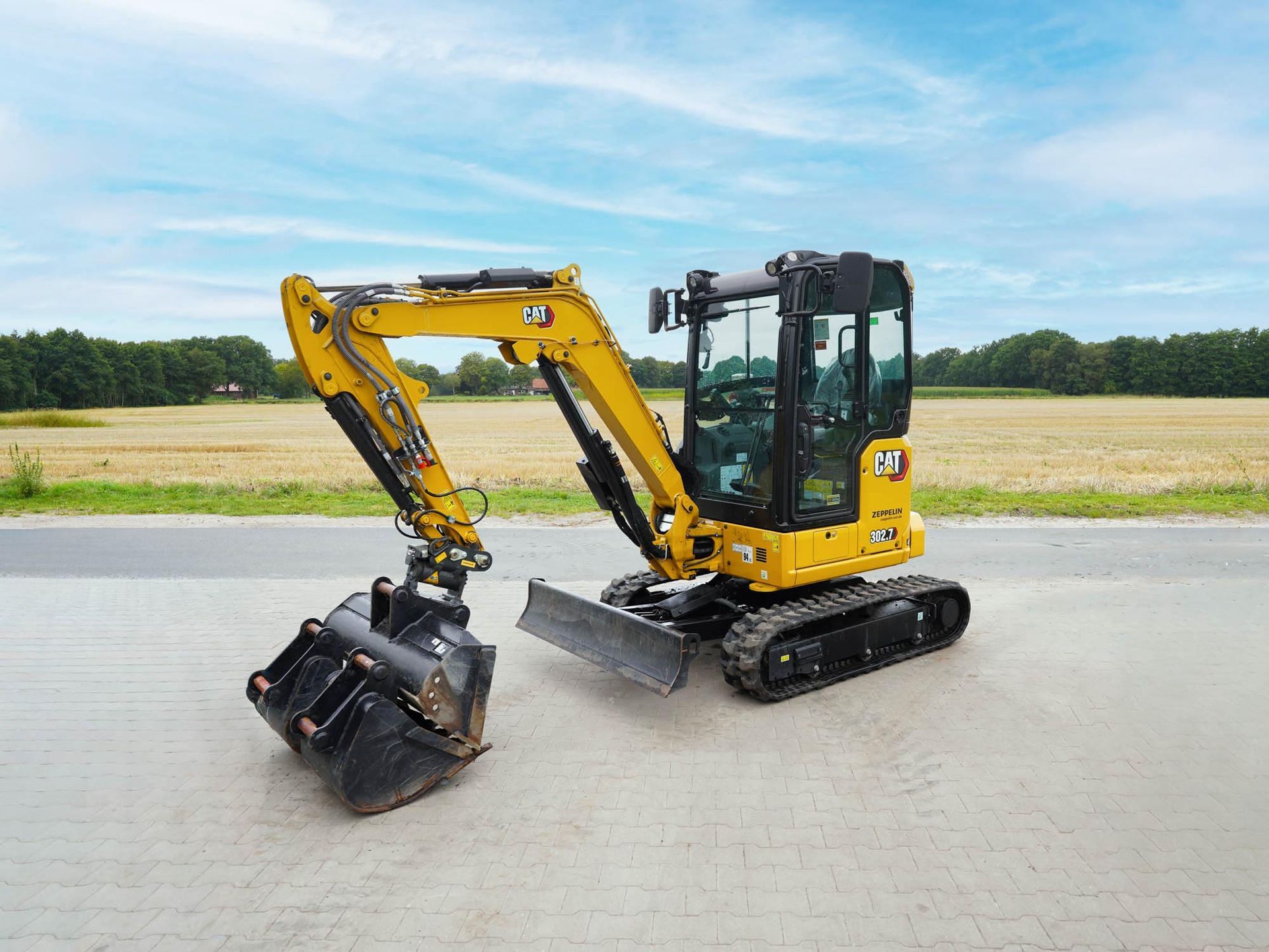 Gelb-schwarzer CAT-302-7-Minibagger auf einer gepflasterten Fläche.
