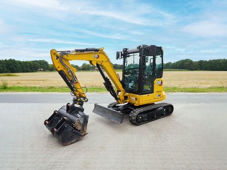 Gelb-schwarzer CAT-302-7-Minibagger auf einer gepflasterten Fläche.