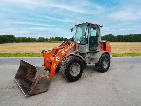 Radlader von Weycor in orange auf einer gepflasterten Fläche.
