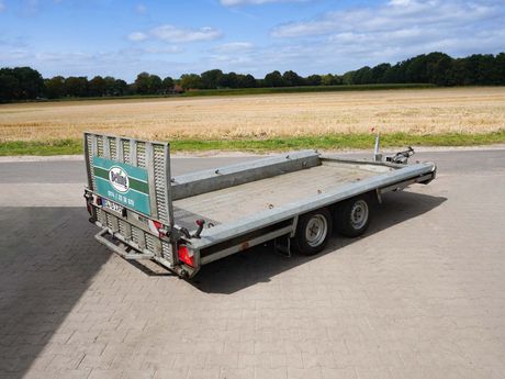 Ein grauer Anhänger steht auf einer gepflasterten Fläche.