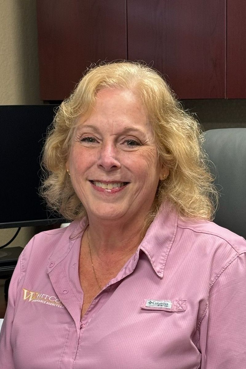 A woman in a pink shirt is smiling for the camera while sitting in a chair.