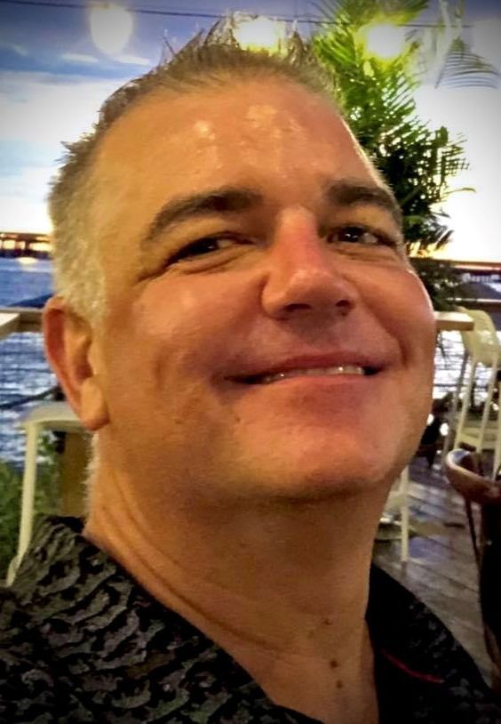 A woman wearing glasses and a red shirt is smiling for the camera.