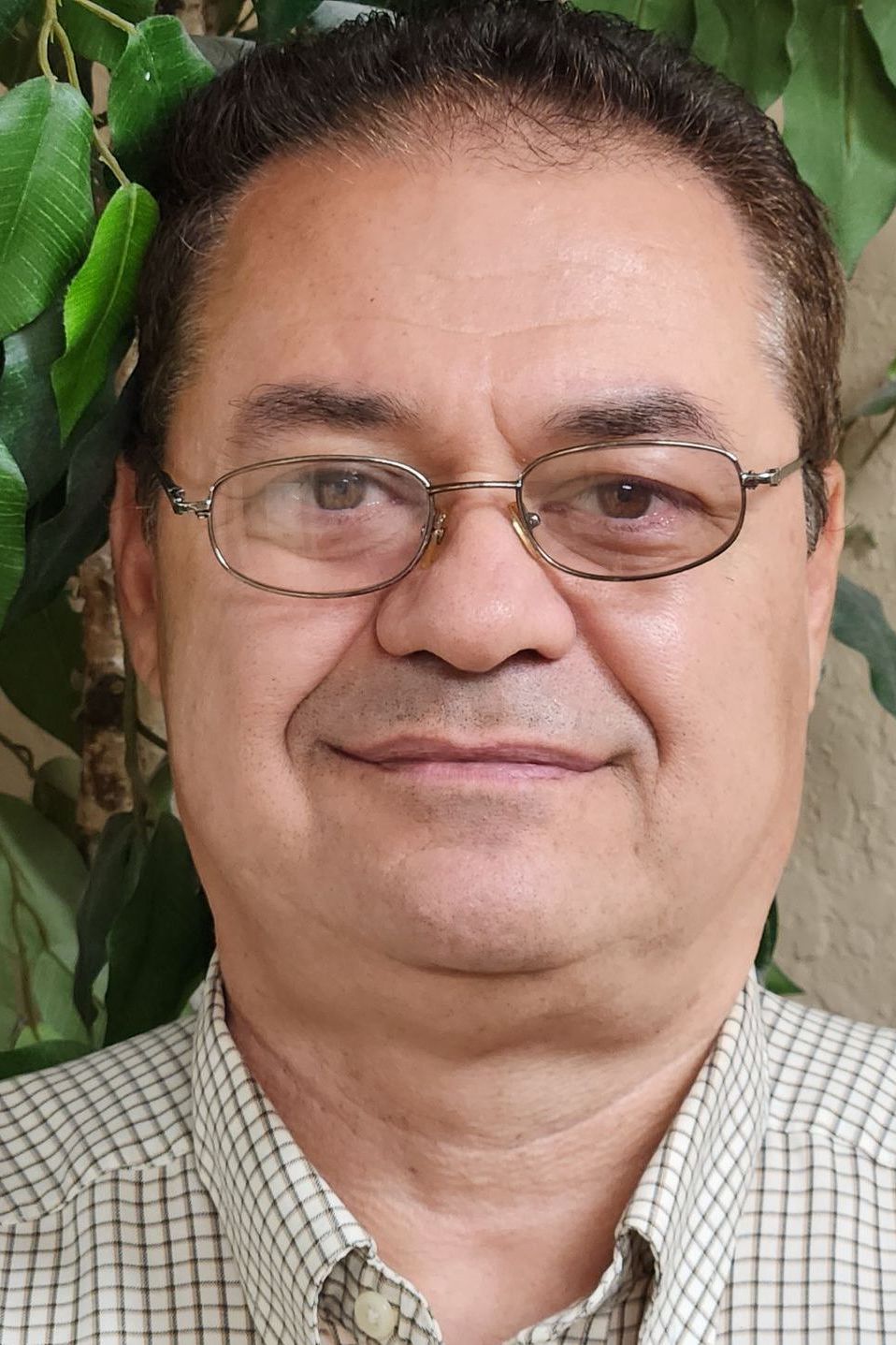 A man wearing glasses and a plaid shirt is smiling for the camera.