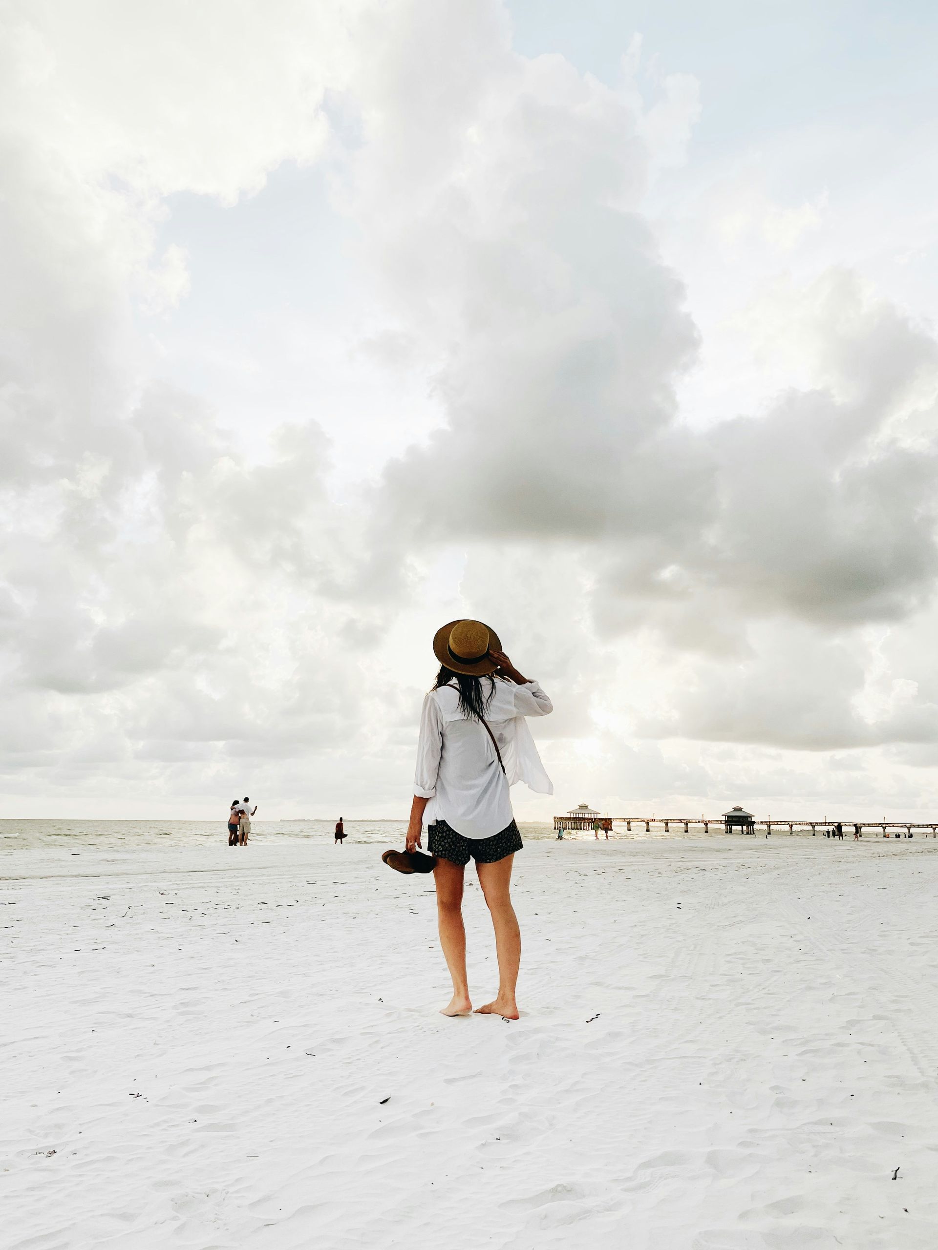 A woman is standing on a beach looking at the ocean.