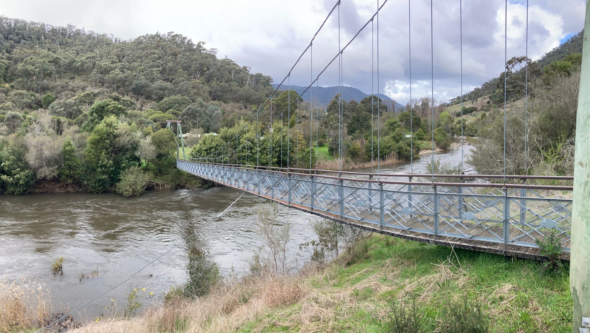 Hume & Hovell Walking Trail suspension bridge over a river with mountains in the background