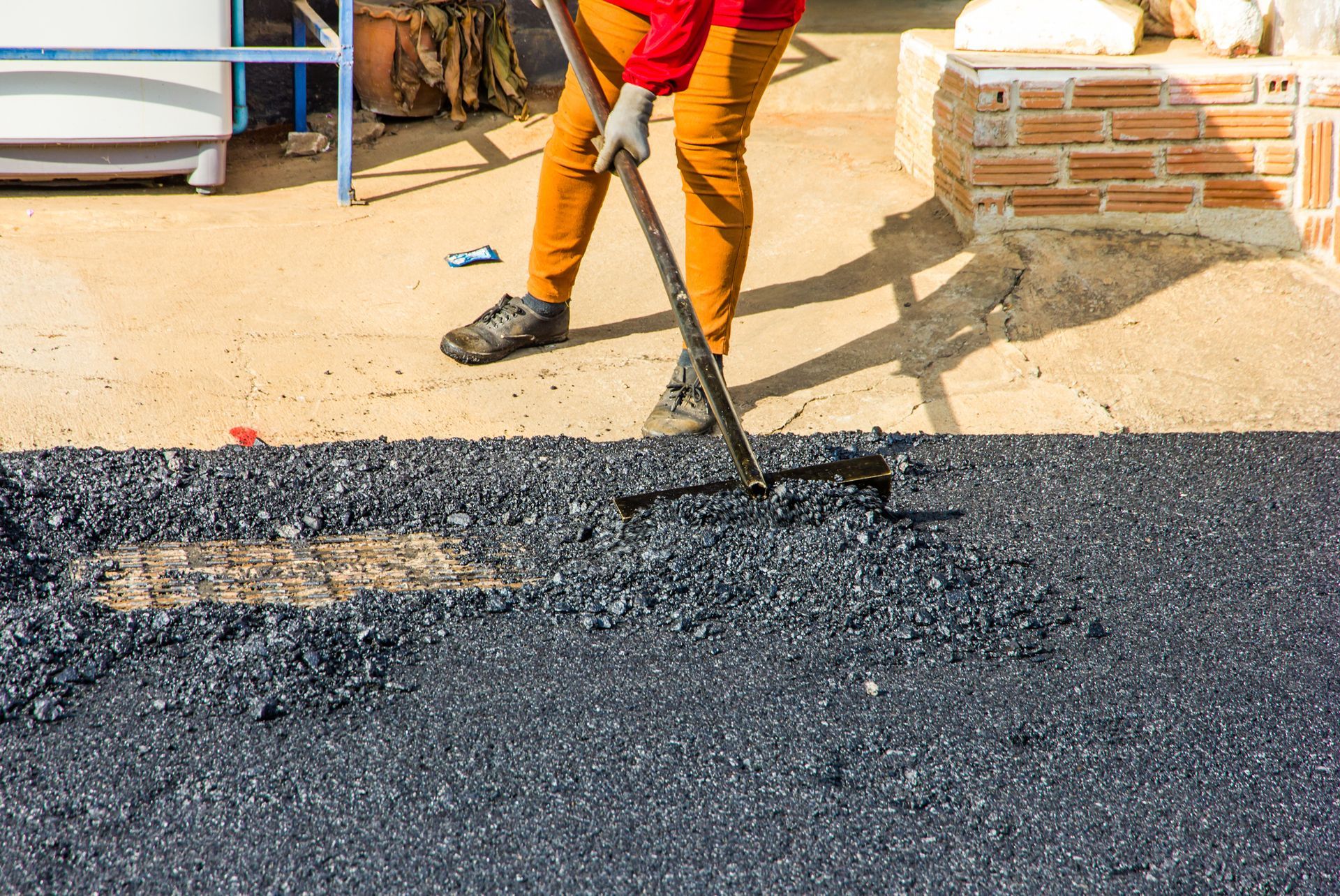 A worker is leveling the asphalt.