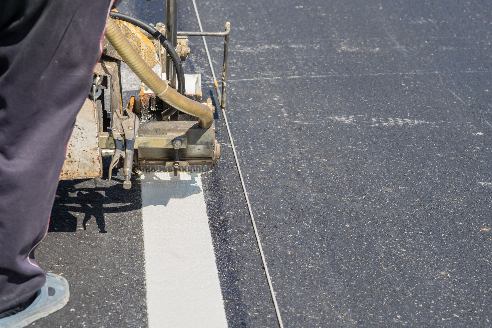 A Man Is Using A Machine To Paint A White Line On The Road | Middletown, OH | Affordable Paving Company