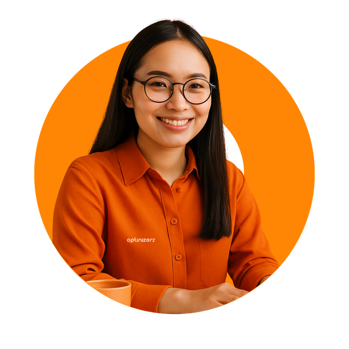 Woman with glasses smiling, wearing orange shirt, in front of orange circle.