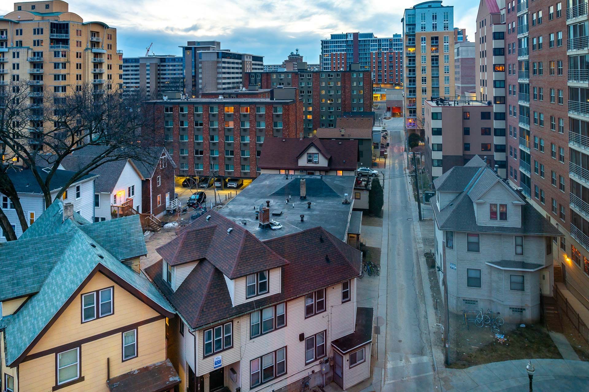 Cityscape with houses in the foreground and tall buildings in the background, gray sky.