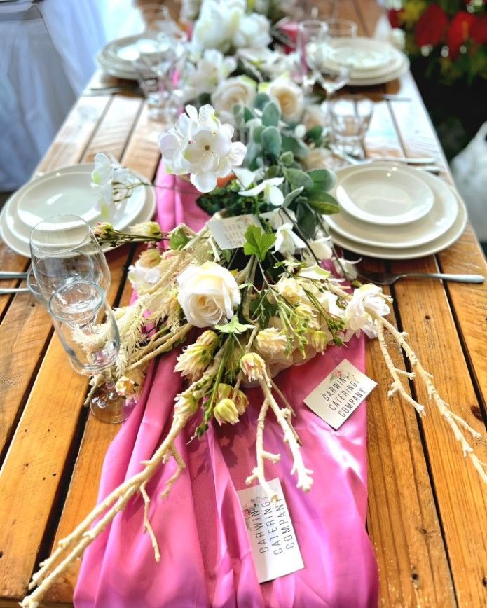 A Wooden Table With Plates, Glasses, and Flowers on It — Darwin Catering Company in Brinkin, NT