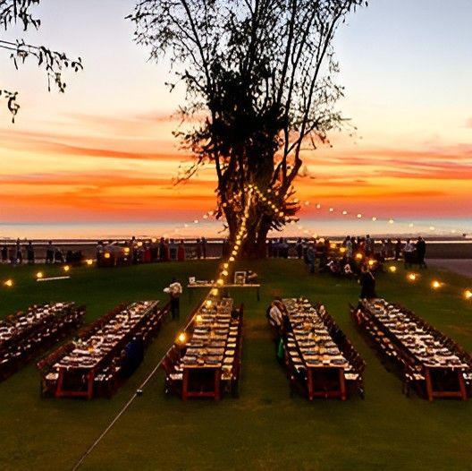 A Row of Long Tables in a Field With a Sunset in the Background — Darwin Catering Company in Brinkin, NT