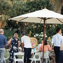 A Group of People Are Gathered Under an Umbrella at a Table — Darwin Catering Company in Brinkin, NT